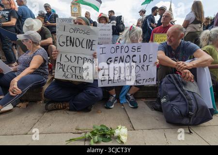 London, Großbritannien. September 2025. Sitzende und stehende Demonstranten halten Schilder mit der Aufschrift Ich LEHNE VÖLKERMORD AB Ich UNTERSTÜTZE DIE PALÄSTINENSISCHE AKTION während eines friedlichen Protests im Vereinigten Königreich. Weiße Blumen auf dem Boden deuten auf Gedenken oder Solidarität hin. Verteidigen Sie unsere Geschworenen gegen das Verbot der Palästinensischen Aktion, indem über 1000 Menschen sich verpflichten, Zeichen zu halten, die gegen das Verbot von Labour verstoßen, und zeigen Unterstützung für die verbotene Gruppe. Penelope Barritt/Alamy Live News Stockfoto