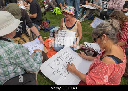 London, Großbritannien. September 2025. Auf Gras sitzende Teilnehmer bereiten handgemachte Protestzeichen gegen Völkermord und Unterstützung der Palästinensischen Aktion vor. Verteidigen Sie unsere Geschworenen gegen das Verbot der Palästinensischen Aktion, indem über 1000 Menschen sich verpflichten, Zeichen zu halten, die gegen das Verbot von Labour verstoßen, und zeigen Unterstützung für die verbotene Gruppe. Penelope Barritt/Alamy Live News Stockfoto