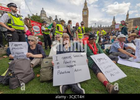 London, Großbritannien. September 2025. Die Demonstranten versammeln sich friedlich auf dem Gras vor dem Palace of Westminster in London, wobei Big Ben im Hintergrund sichtbar ist. Die Teilnehmer halten Zeichen, die sich gegen den Völkermord aussprechen und ihre Solidarität mit Palästina und der Palästinensischen Aktion zum Ausdruck bringen. Polizisten beobachten die Demonstration. Verteidigen Sie unsere Geschworenen gegen das Verbot der Palästinensischen Aktion, indem über 1000 Menschen sich verpflichten, Zeichen zu halten, die gegen das Verbot von Labour verstoßen, und zeigen Unterstützung für die verbotene Gruppe. Penelope Barritt/Alamy Live News Stockfoto