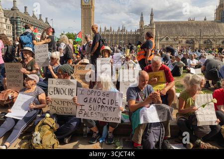 London, Großbritannien. September 2025. Demonstranten, die vor dem Palace of Westminster in London sitzen, halten Schilder mit der Aufschrift „Ich bin gegen den Völkermord und unterstütze die Palästinensische Aktion“. Der Protest hebt die Solidarität mit Palästina und die Opposition gegen staatliche Gewalt hervor, wobei Big Ben im Hintergrund sichtbar ist. Verteidigen Sie unsere Geschworenen gegen das Verbot der Palästinensischen Aktion, indem über 1000 Menschen sich verpflichten, Zeichen zu halten, die gegen das Verbot von Labour verstoßen, und zeigen Unterstützung für die verbotene Gruppe. Penelope Barritt/Alamy Live News Stockfoto