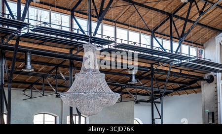 Kristalllüster hängt anmutig von einer hohen Decke, in natürliches Licht getaucht, und unterstreicht die Eleganz des geräumigen Innenraums mit seinem komplexen d Stockfoto