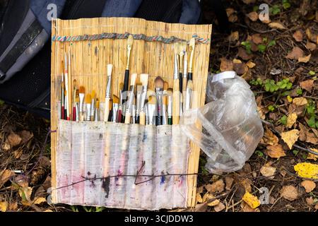 Der Künstler mischt mehrfarbige Farben auf einer Palette zum Zeichnen. Eine Palette mit Farben und Pinseln zum Zeichnen. Stockfoto
