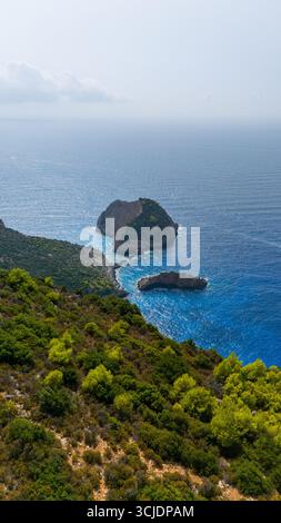 Blick aus der Vogelperspektive auf Agios Andreas Höhleninsel mit felsiger Küste, blauem Ionischen Meer, grünem Hügel im Vordergrund und kleiner Insel in der Nähe der Hauptinsel Stockfoto