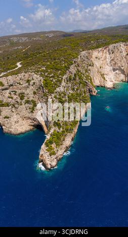 Zakynthos Griechenland Küstenklippen mit steilen Felswänden, grünem Kiefernwald auf der Spitze und türkisfarbenen Wellen des Ionischen Meeres, die unter der Luft zusammenbrechen Stockfoto