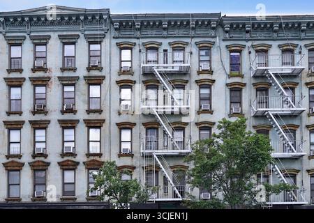 Altes New Yorker Apartmentgebäude mit externer Feuertreppe und rostigen Fensterstürzen Stockfoto