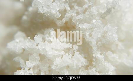 Aus nächster Nähe sehen Sie natürliche weiße Meersalzkristalle, die ihre grobe Textur, unregelmäßige Formen und glänzende Oberfläche zeigen, die häufig beim Kochen und im Meer verwendet wird Stockfoto