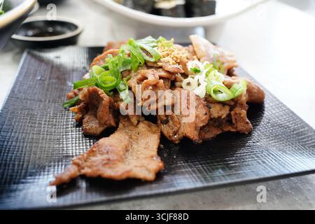 Traditionelles koreanisches Bulgogi-Rindfleischgericht mit grünen Zwiebeln auf schwarzer Platte Stockfoto