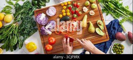 Frisches Gemüse und Obst, Überkopf-Ansicht der Hände Vorbereitung einer farbenfrohen Auswahl an frischem Obst und Gemüse auf einem Holz Stockfoto