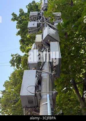 Telekommunikationsturm umgeben von grünem Laub vor klarem blauem Himmel Hintergrund. Mobiles Foto Stockfoto