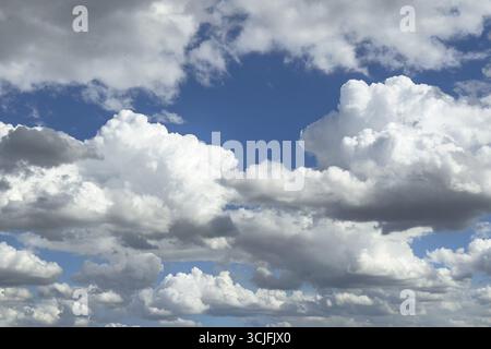 Viele weiße Altocumulus-Wolken bilden Wolken unter einem hellblauen Himmel, die international durch Lücken in der Wolkendecke zu sehen sind Stockfoto
