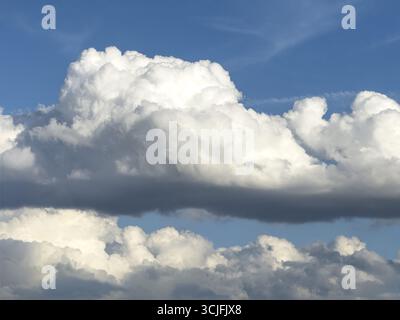 Stratocumulus in der Bildmitte, dichte Wolkendecke von vielen Cumuluswolken im Hintergrund, hellblauer Himmel darüber, international Stockfoto
