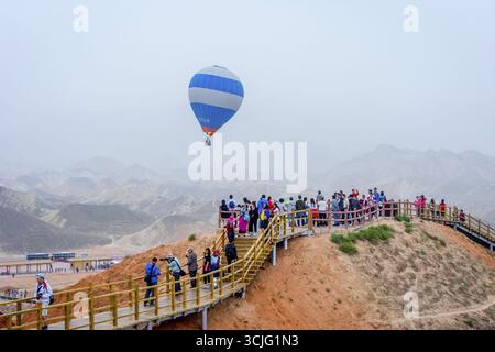 ZHANGYE, CHINA - 25. JUNI: Heißluftballon fliegt über der Menge im Rainbow Mountains Zhangye Danxia National Geopark. Juni 2016 Stockfoto