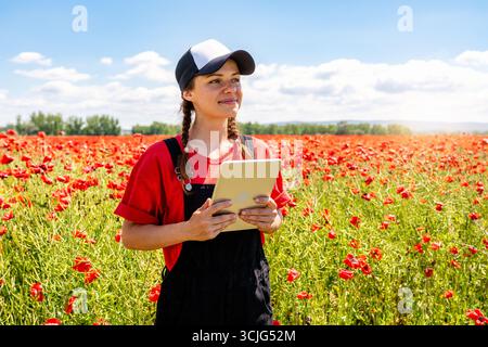 Junge Agrarwissenschaftlerin mit digitaler Tablette in der Nähe des Wildblumenfeldes. Stockfoto