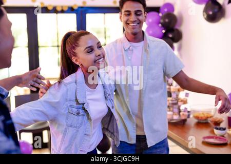 Freunde feiern zu Hause, lächeln und feiern gemeinsam festliche Partys Stockfoto