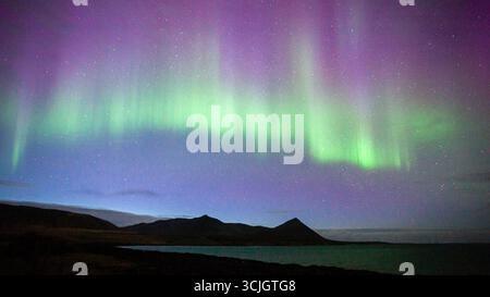 Nordlichter, aurora borealis, die sich über den Himmel mit Bergsilhouetten erstrecken Stockfoto