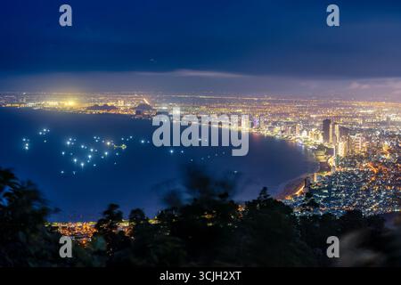 Panoramablick auf da Nang bei Nacht vom Ban Co Peak, mit funkelnden Lichtern der Stadt, Hochhäusern, beleuchteten Brücken über den Han River und Stockfoto