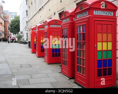 Ikonische rote Telefonboxen mit Pride LGBTQ-Flaggen und -Farben. Covent Garden, London, Großbritannien Stockfoto