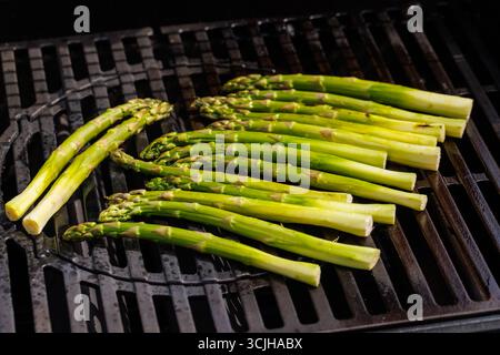 Frische Spargelstangen brutzeln auf einem heißen Grill, Saiblinge und rauchiges Aroma Stockfoto