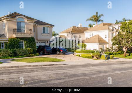Vorstadtstraße mit Häusern in der Gegend von Los Angeles, gesäumt von Bäumen unter sonnigem Himmel Stockfoto