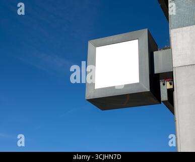 Leeres quadratisches Ladenschild, das auf dem Ladengebäude montiert ist, mit klarem blauem Himmel im Hintergrund. Platzhalter für Branding, Logodesign oder Store-Name PR Stockfoto