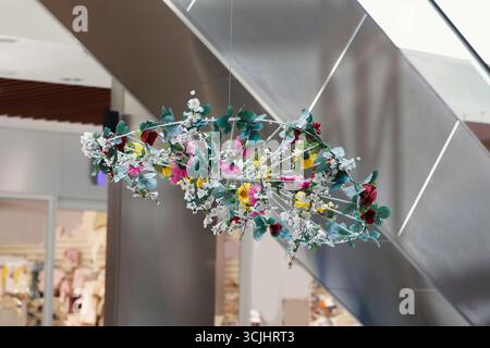 Ein großer, schöner dekorativer Hut aus natürlichen Materialien, geschmückt mit bunten Blumen und Grün, in einem modernen Einkaufszentrum Stockfoto