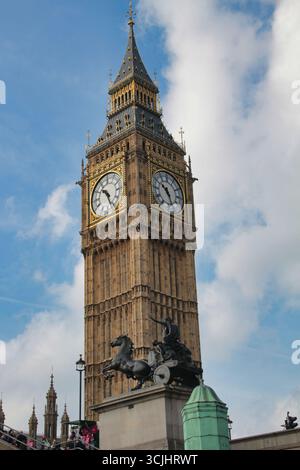 Der berühmte Big Ben Uhrenturm vor einem blauen Himmel: Eine detaillierte Nahaufnahme von Londons berühmtem Wahrzeichen, das seinen komplizierten goldenen und verwitterten Stein betont Stockfoto