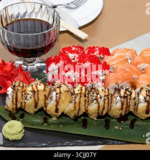 Sushi-Brötchen mit Lachs, Tobiko und Tempura auf Schieferplatte, realistischer Stil, auf weißem Holztisch, Konzept Stockfoto