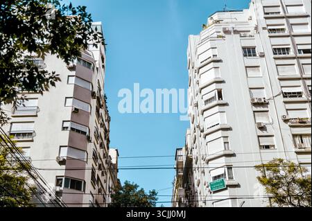 Buenos Aires, Argentinien – 22. Dezember 2022: Wohnhäuser aus der Mitte des Jahrhunderts mit Art-Deco-Elementen ragen entlang einer grünen Straße von Recoleta. Stockfoto