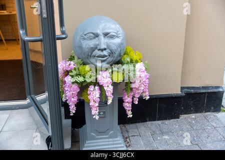 Moskau, Russland, 25. August 2025, Eine skurrile Mondstatue mit Blumen vor einem Gebäude in Moskau. Stockfoto