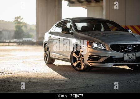 Der silberne Volvo S60 parkt unter einer Brücke. Eckansicht der schwedischen sportlichen Limousine in Sonnenstrahlen, Betonsäulen im Hintergrund. Stockfoto
