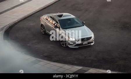 Silver Volvo S60 auf einer Straße - Blick von oben. Dreiviertelansicht der schwedischen sportlichen Limousine, die auf der Außenseite der Straßenkurve geparkt ist. Stockfoto
