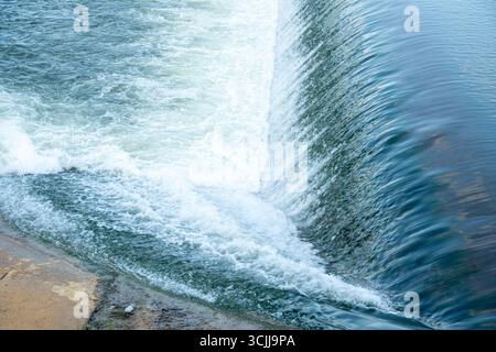 Das Wasser fließt einen Wasserfall hinunter und schafft eine wunderschöne und kraftvolle Szene. Das Wasser ist weiß und blau, und es sieht aus, als würde es herunterstürzen Stockfoto