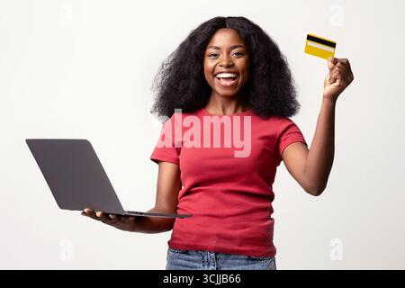 Konzept Für Online-Zahlungen. Fröhliche Afroamerikanische Frau Mit Kreditkarte Und Laptop Stockfoto