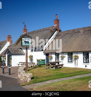 Ein Blick an einem sonnigen Sommertag auf die Hauptstraße des Dorfes Etal in Northumberland bei Berwick, in Richtung des reetgedeckten Pubs The Black Bull Stockfoto