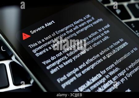 Testbildschirm für Notrufmeldungen auf Smartphone neben der Laptop-Tastatur, detaillierte Textansicht. Stafford, Vereinigtes Königreich, 7. September 2025 Stockfoto