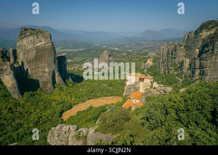 Meteora Griechenland Klöster auf hohen Felsformationen umgeben von grünen Tälern und fernen Bergen unter klarem blauen Sommerhimmel Stockfoto