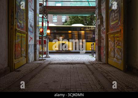 Ein gelber BVG-Bus fährt am Eingang zu einem typischen Berliner Hinterhof/Hof, Berlin, Deutschland, Europa vorbei Stockfoto