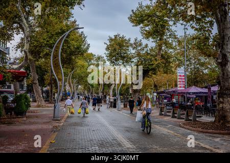 In Yalova, Türkei, spazieren und radeln die Menschen entlang einer von Bäumen gesäumten Fußgängerzone mit modernen Straßenlaternen und Cafés. Yalova, Provinz Yalova, Türkisch Stockfoto