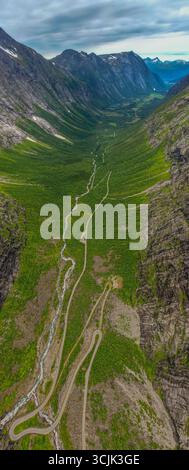 Aus der Vogelperspektive auf ein dramatisches norwegisches Tal mit einer kurvenreichen Straße, die durch üppige grüne Berghänge führt Stockfoto
