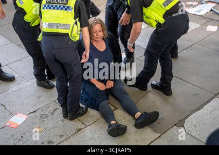 Palästina-Aktion Demo 6. September 2025. Eine Frau sitzt auf dem Boden und wird verhaftet, weil sie ein Schild trägt: „Ich unterstütze die Palästinensische Aktion, ich bin gegen Völkermord“. Stockfoto