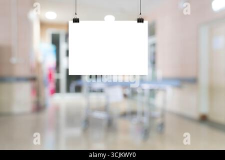 Leeres weißes Poster Mockup hängt mit Clips im Krankenhaus- oder Büroflur, isoliert auf verschwommenem Hintergrund, leere Werbe- oder Werbeanzeigen Stockfoto