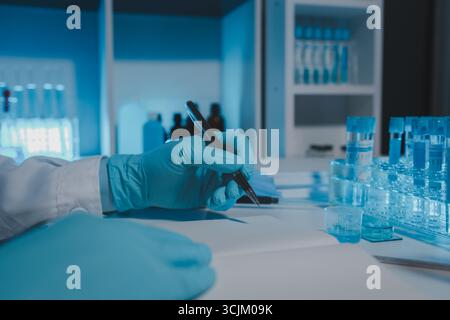 Ein Wissenschaftler arbeitet im Labor und nimmt die Ergebnisse des Experiments zur Kenntnis, Papiere tragen den Namen der Chemikalie, nachdem alle Proben untersucht und resu werden Stockfoto