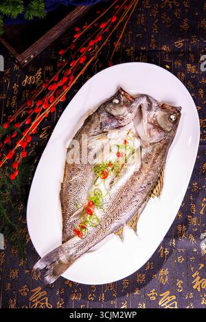 Gedämpfter ganzer Seebarsch mit Ingwer, Scallion und Chili auf weißer Platte Stockfoto