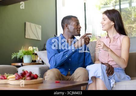Zu Hause genießen Sie gemeinsam Wein, feiern Sie mit Lächeln und Unterhaltung Stockfoto