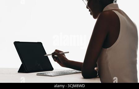 Ein fokussierter Profi verwendet einen Stift auf einem Tablet, um zu arbeiten, zu lernen oder zu entwerfen. Ideal für moderne Arbeit, Technologie, Kreativität, Stockfoto