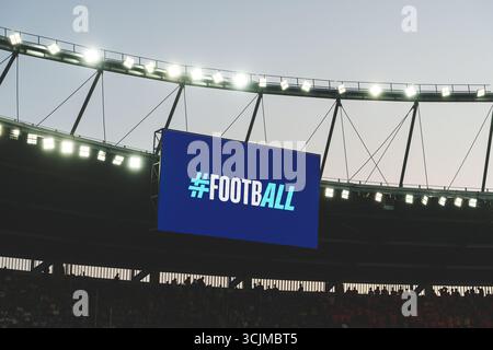 Large stadium screen showing hashtag football sign under bright lights  Stockfoto