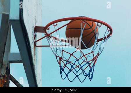 Basketball, der durch das Netz schwingt in einem aufregenden Spiel, Einer Nahaufnahme eines Basketballs, der kurz vor dem Betreten des Basketballs steht. Stockfoto