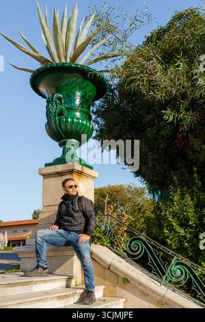 Mann sitzt bei einer dekorativen Vase im Zappeion-Garten in Athen, Griechenland. Stockfoto