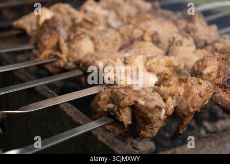Saftige Fleischscheiben bereiten sich auf dem Feuer vor. Leckerer Shish Kebab auf Spießen. Gegrilltes mariniertes Grillfleisch - Schaschlik auf Schweinefleisch Stockfoto