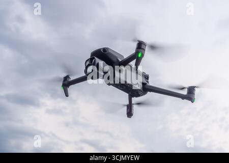 Die Drohne schwingt über eine malerische Landschaft mit moderner Technologie und Schönheit der Natur an einem bewölkten Nachmittag. Ein schwarzer Quadcopter in Close-up ag Stockfoto
